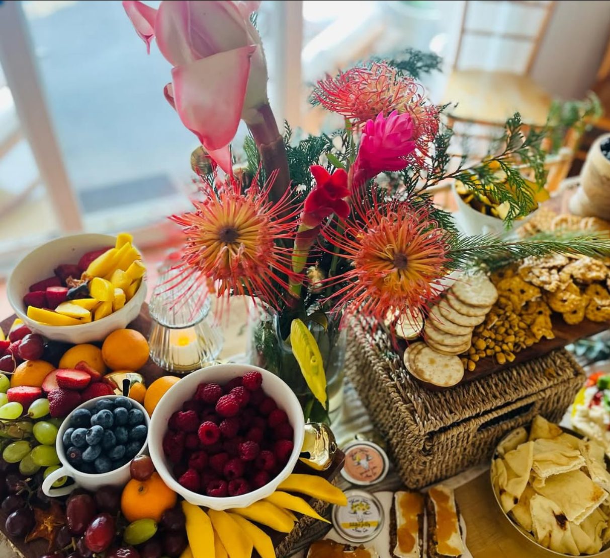 A board of fruit, crackers and cheese with the farm's jars and fresh flowers.