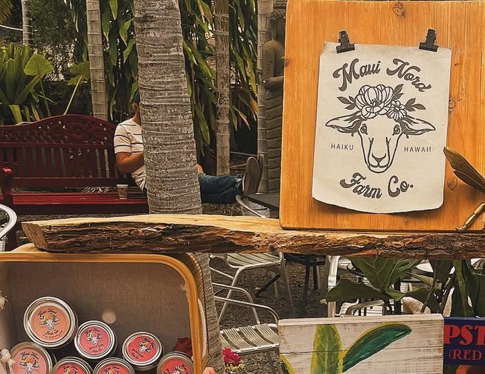 The wooden sheep sign above the market table, with a shelf of jars and tins.