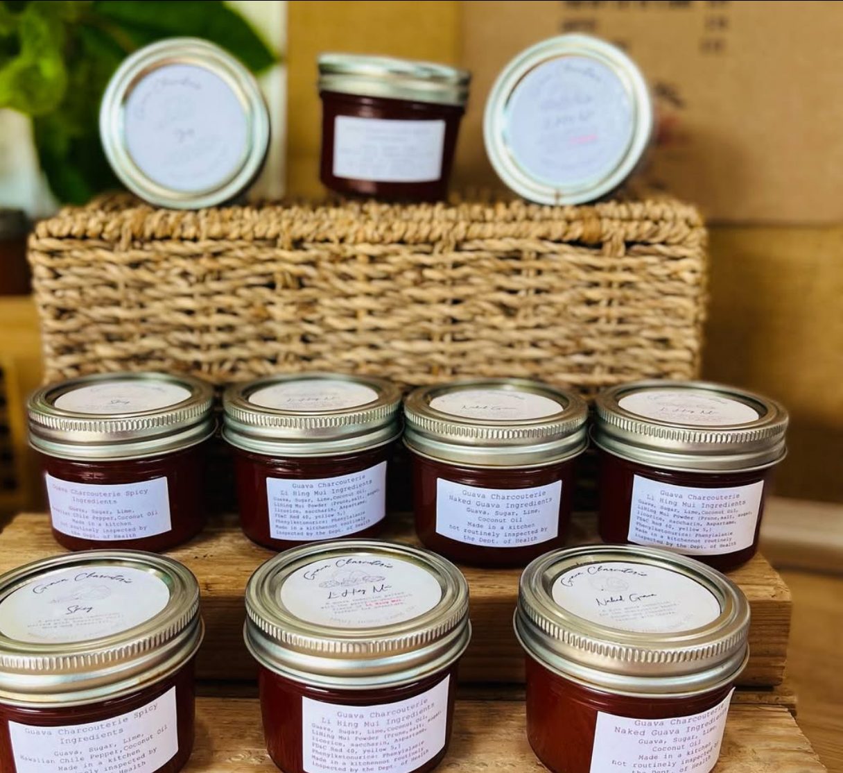 Jars of guava charcuterie paste in three varieties, stacked on a basket.