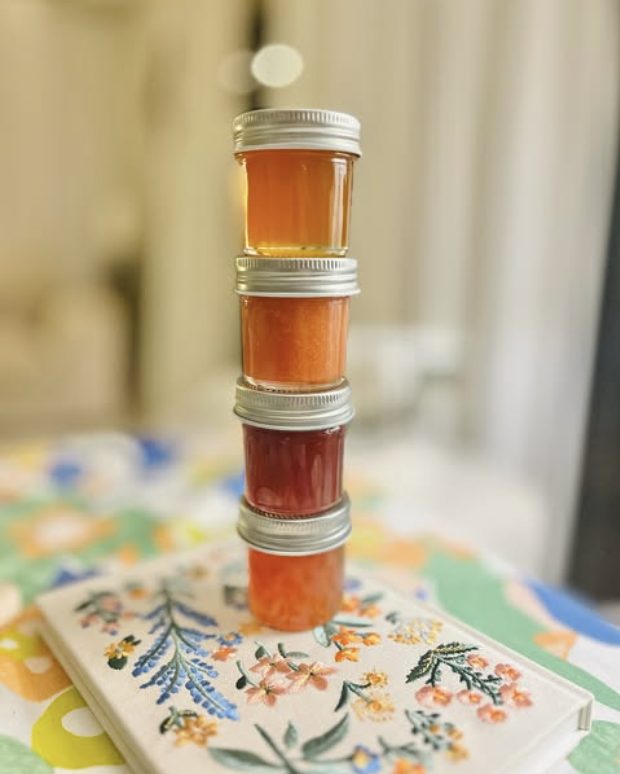 Four jars from the line, stacked on an embroidered cloth.
