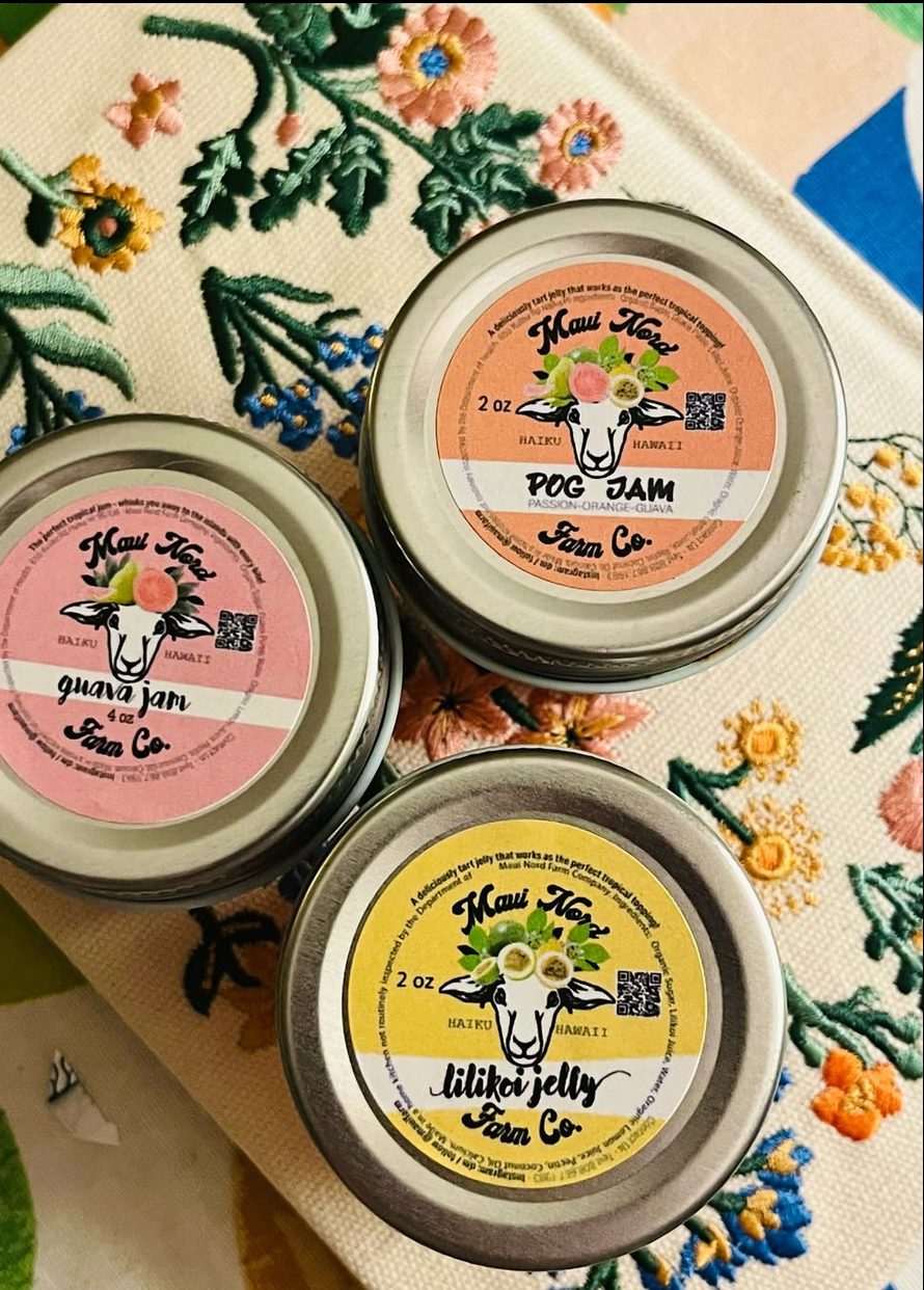 Guava jam, POG jam and lilikoi jelly on an embroidered floral cloth.